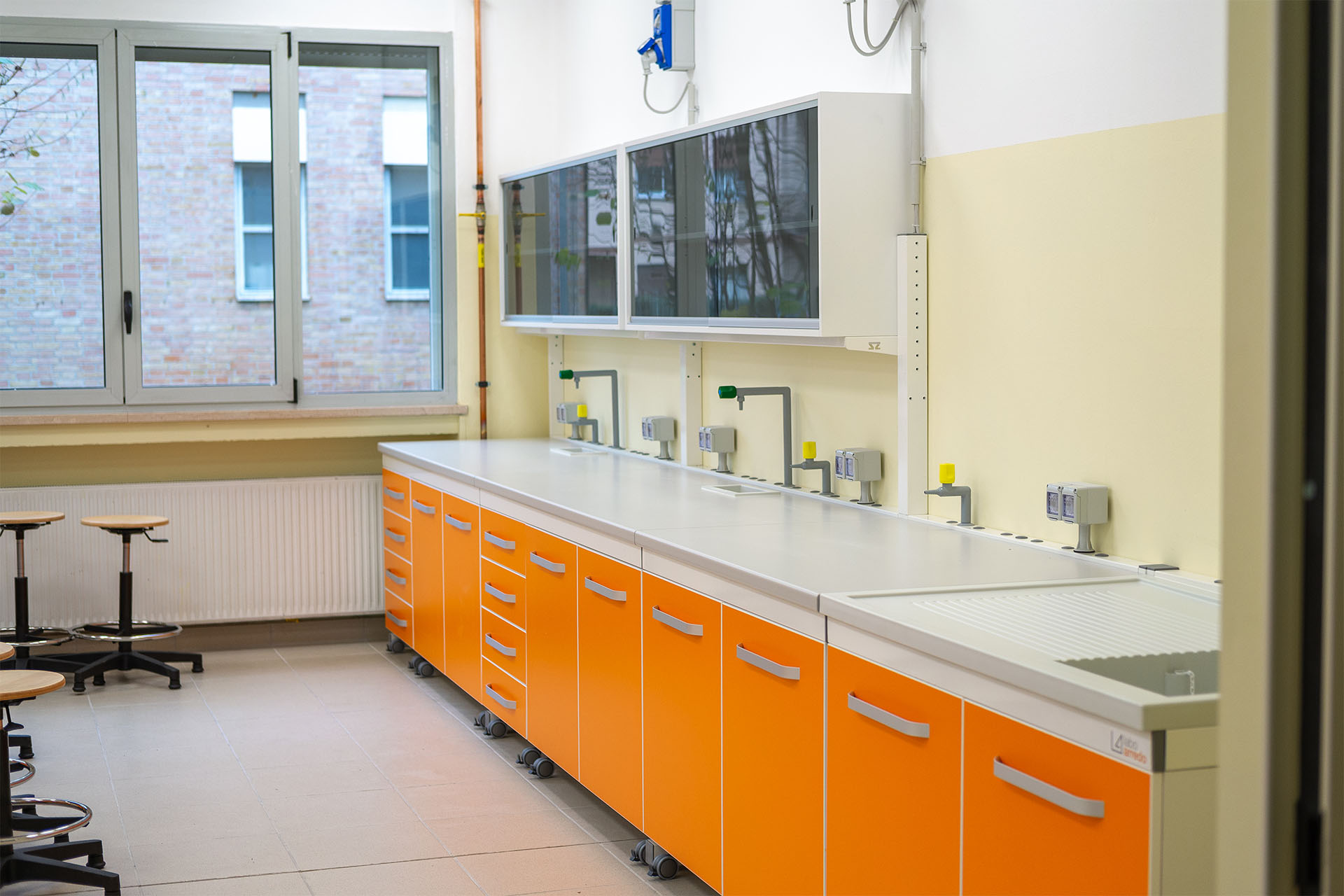 Laboratorio didattico con banchi tecnici arancioni per istituti scolastici, completi di accessori e complementi